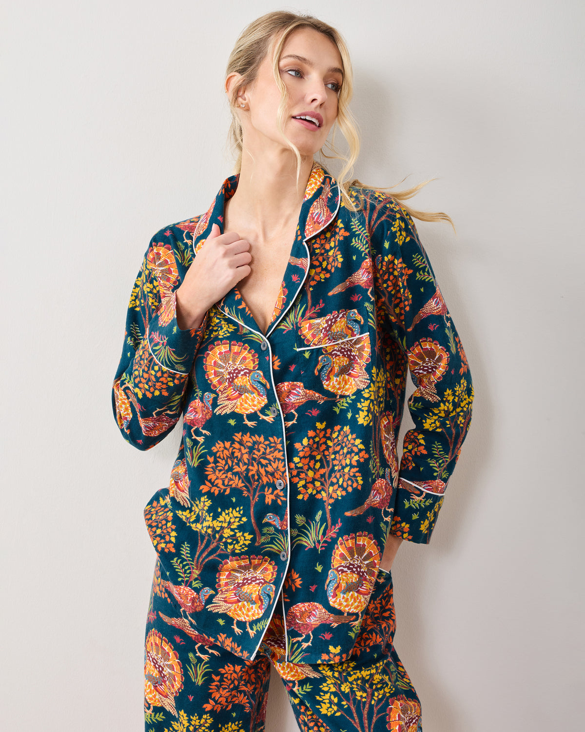 Three-quarter view of a model wearing the Turkey Trot navy pajama set with a turkey and foliage print.