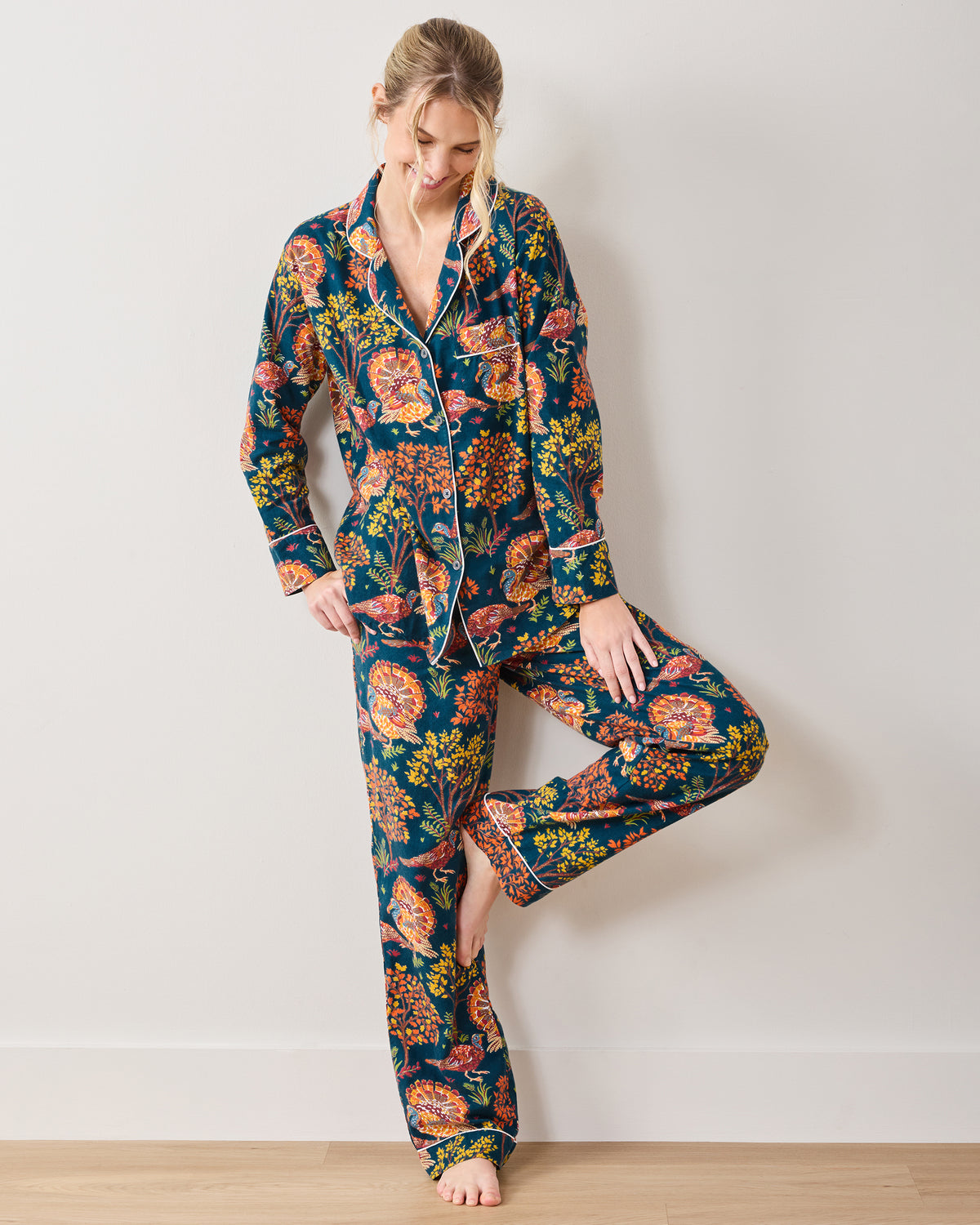 Full-length view of a model wearing the Turkey Trot navy long pajama set with a turkey and foliage print.