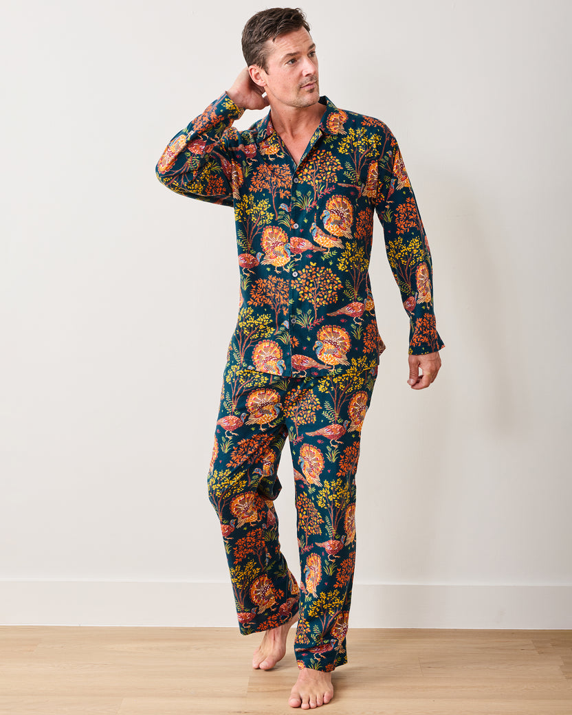Full-length view of a model wearing the navy Turkey Trot long pajama set with colorful turkey and autumn foliage print.