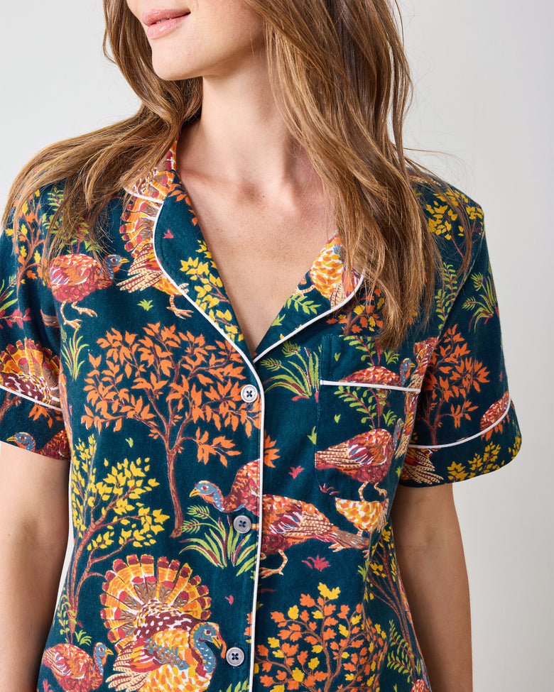 Close front view of the navy Turkey Trot short pajama top with white piping, buttons, chest pocket, and colorful turkey and autumn foliage print.