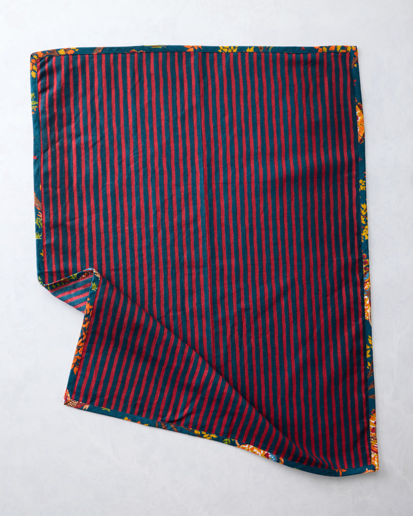 Tea towel showing a red-and-navy striped reverse side with a corner folded back to reveal the turkey print.