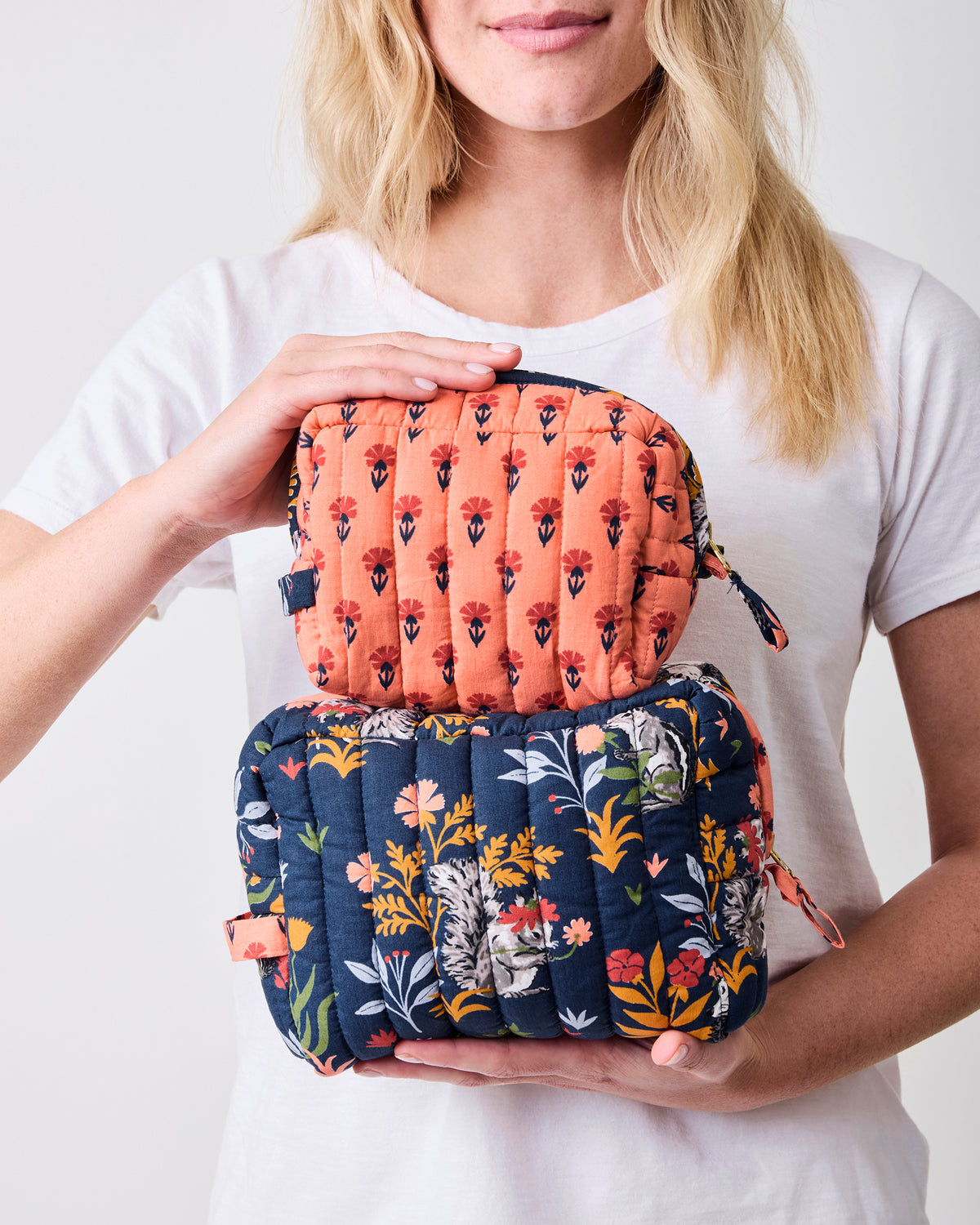 Large quilted indigo pouch opened to show its coral floral-print lining and woodland exterior print.