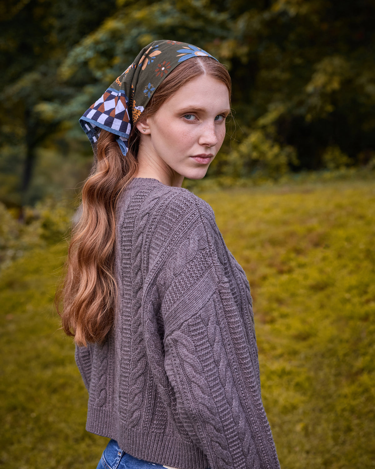 Printed bandana scarf tied over the back of the head, with geometric and floral sections visible.