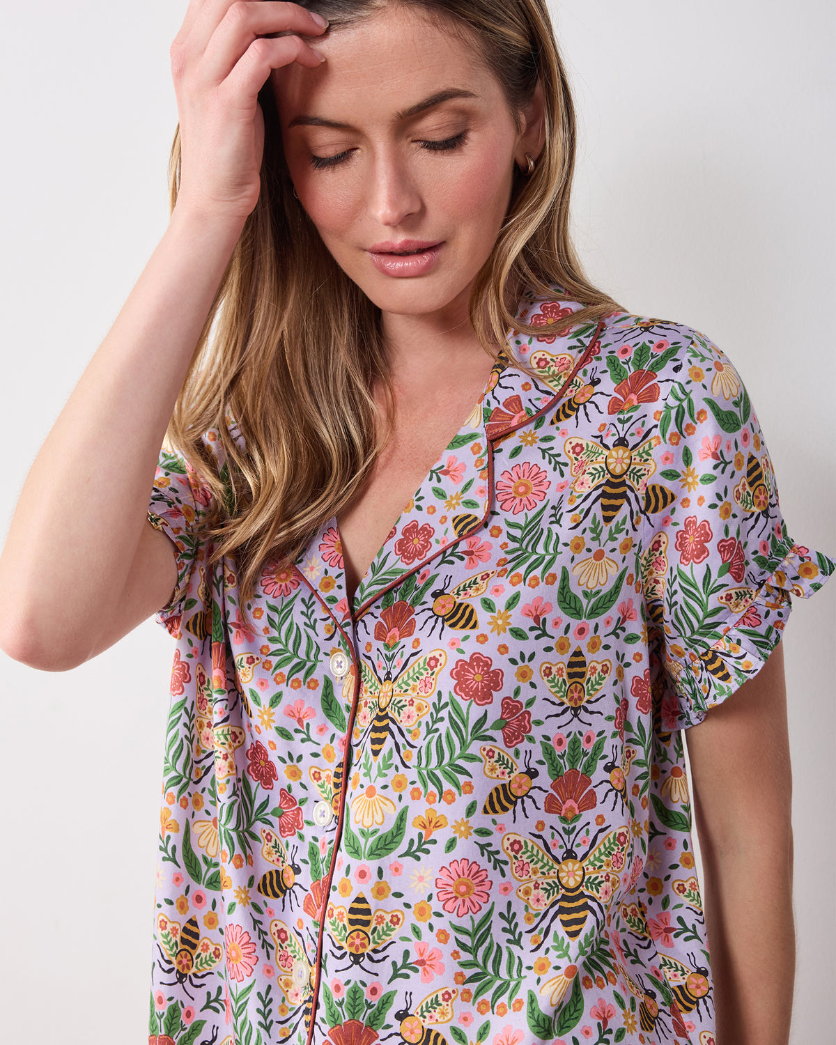 Close-up of the lavender Bee Tapestry pajama top showing its collar, buttons, ruffled sleeve, and bee-and-floral print.