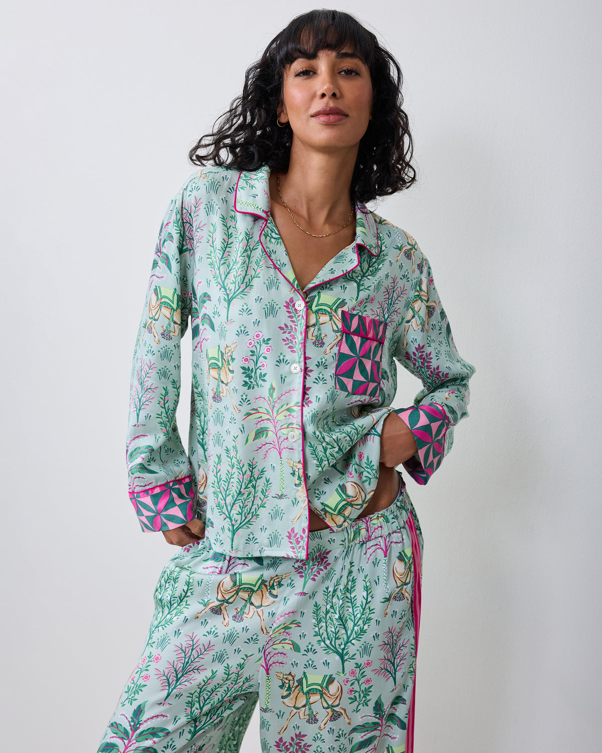 Three-quarter front view of a model wearing the avocado Camel's Courtyard long-sleeve pajama set with a camel-and-botanical print and wide-leg pants.