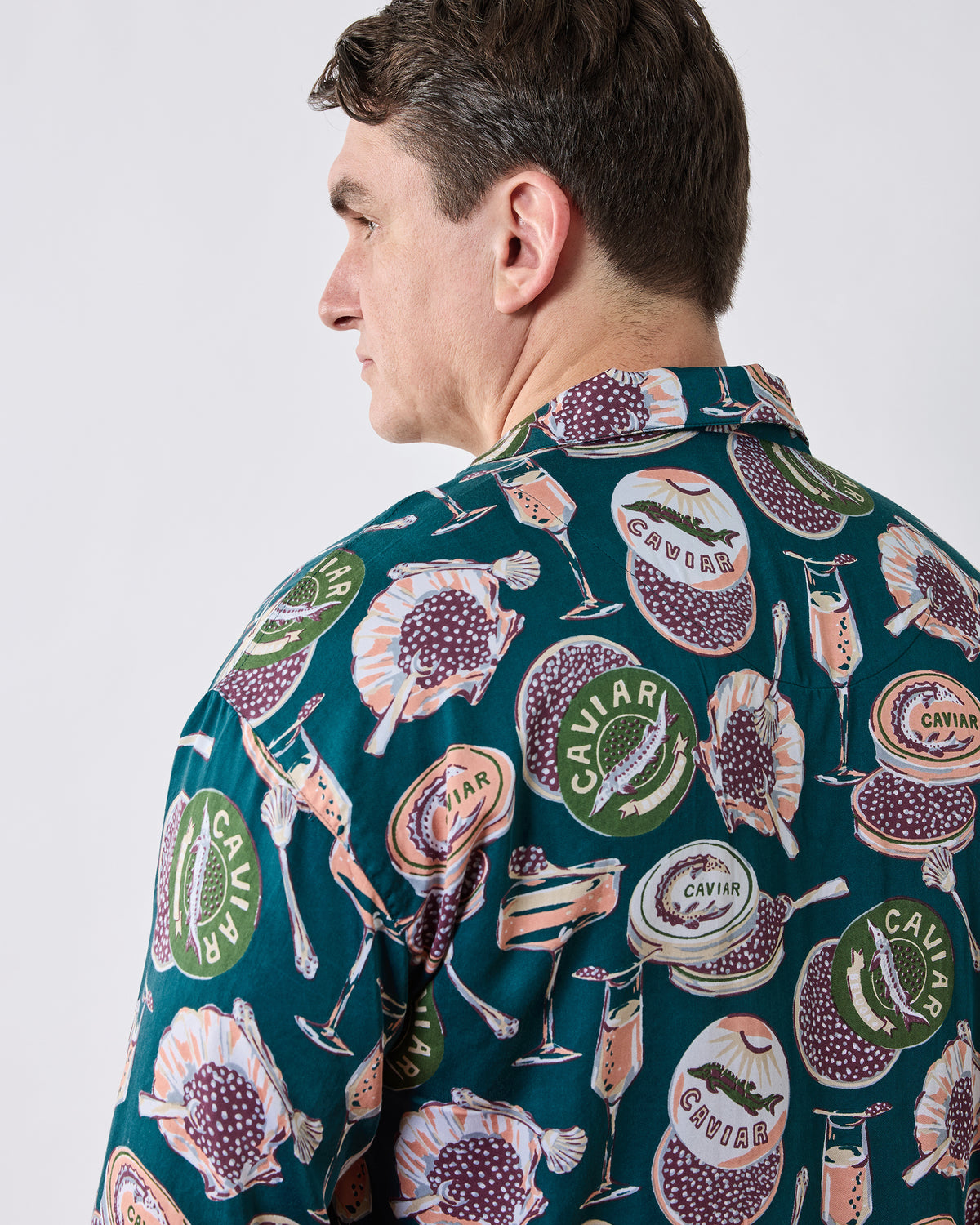 Back and side view of the dark teal long pajama top, showing the collar and full caviar-and-champagne print.
