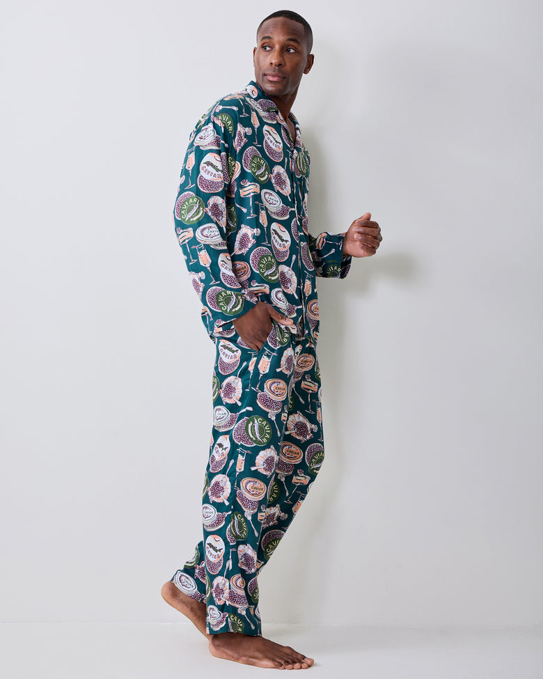 Side view of a person wearing a matching long-sleeve pajama top and full-length pants with a caviar-and-champagne print.