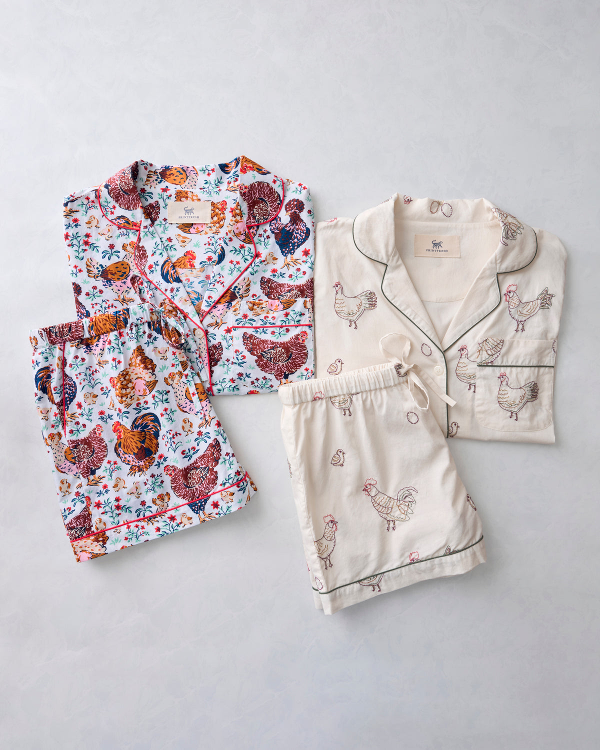 Two chicken-themed short pajama sets displayed together: one colorful chicken print and one cream set with embroidered chicken designs.