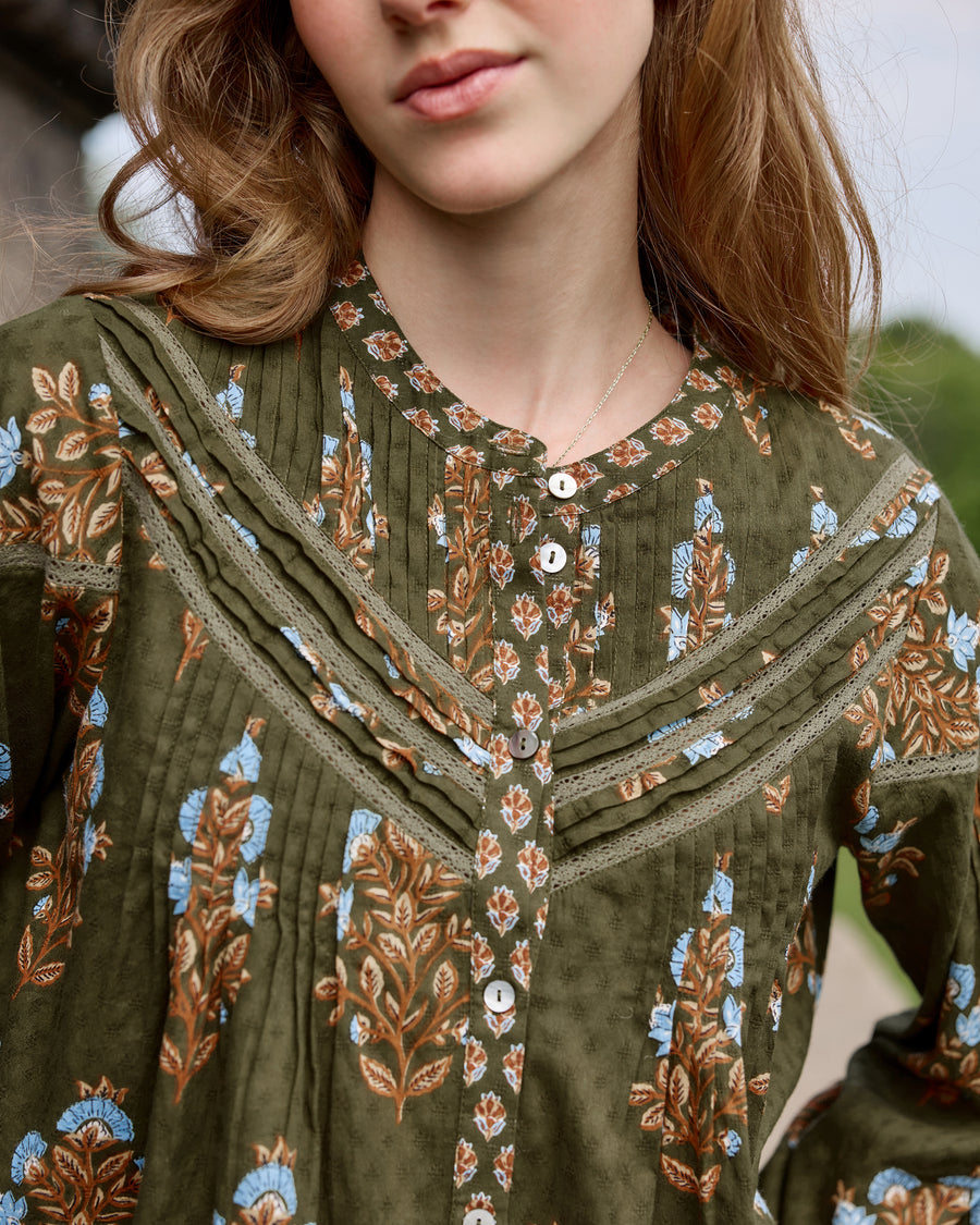 Close-up of the deep olive Belmont blouse showing its floral print, pleated front, lace-trimmed yoke, and button placket.