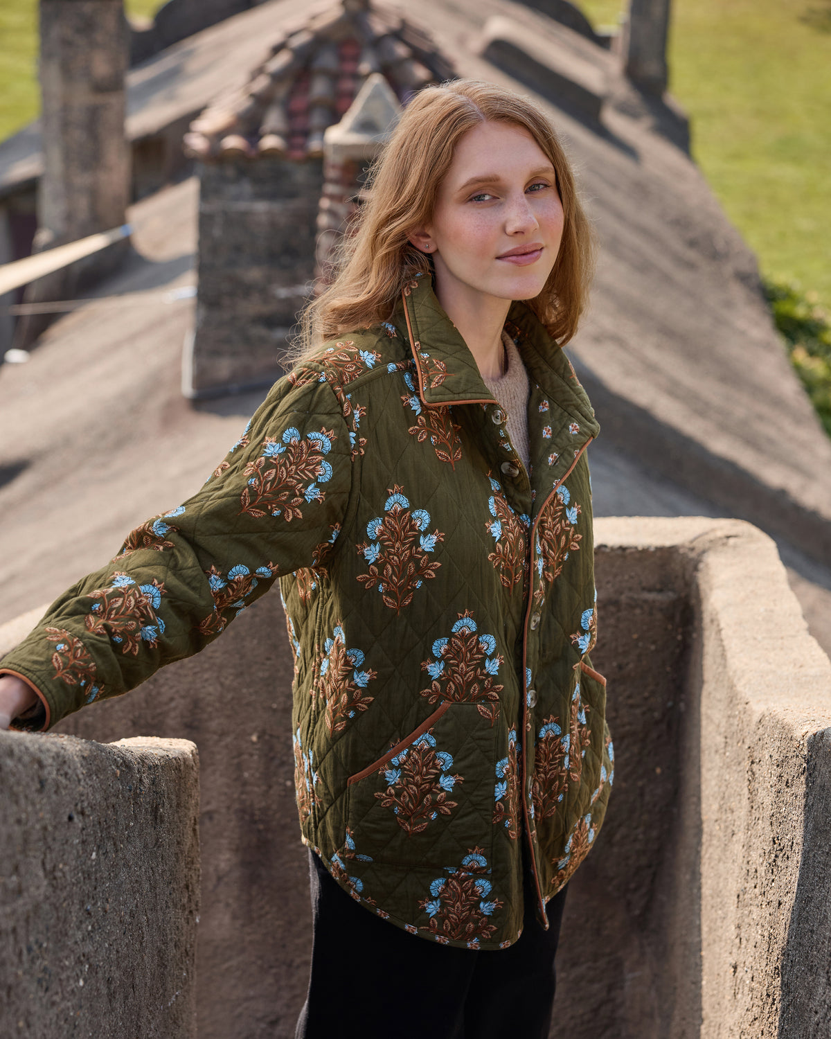 Deep olive floral-print quilted jacket worn buttoned, front three-quarter view.