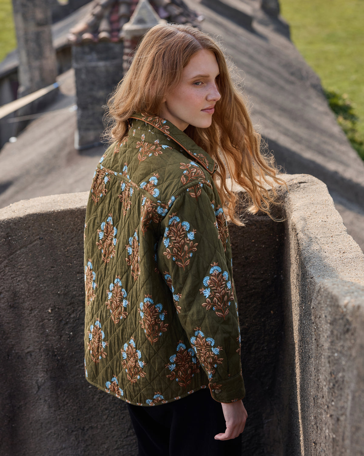 Deep olive floral-print quilted jacket shown from the back on a model.