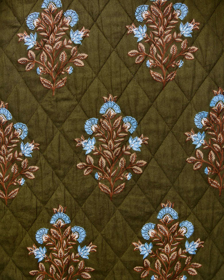 Desert Stamp pattern swatch with repeating blue flowers and brown leafy branches on an olive background with a diamond quilted pattern.