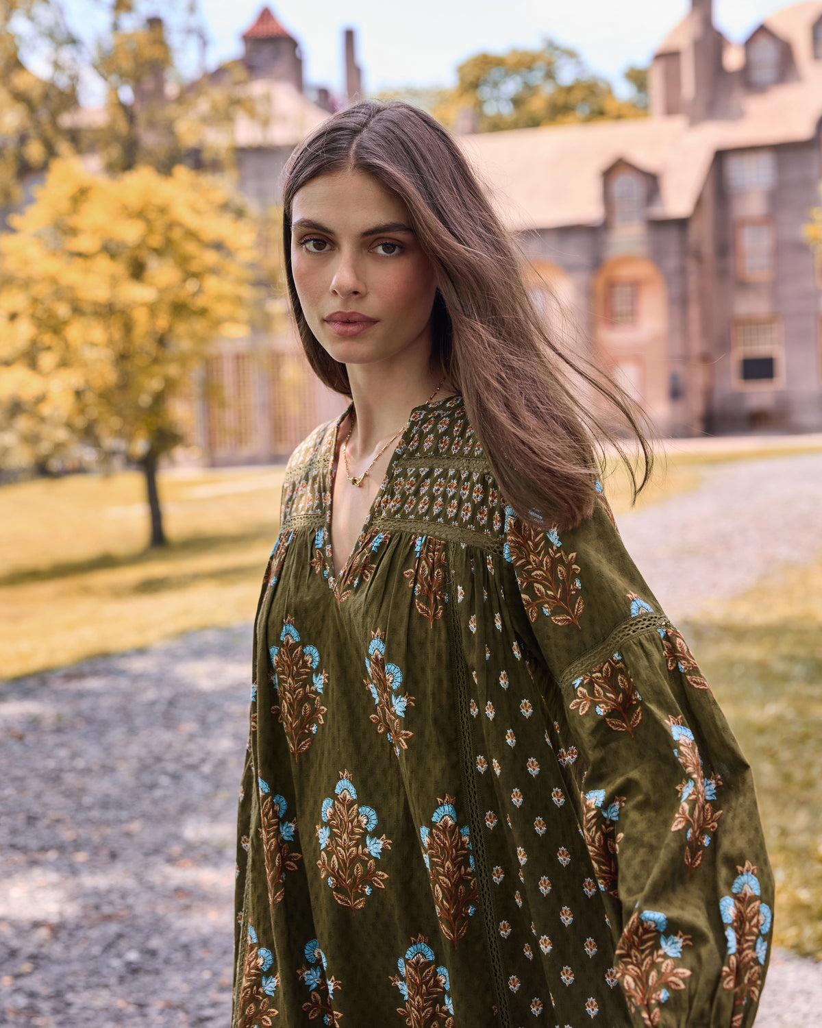 Close view of the deep olive Tallulah dress showing its V-neckline, patterned yoke, and long floral-print sleeves.