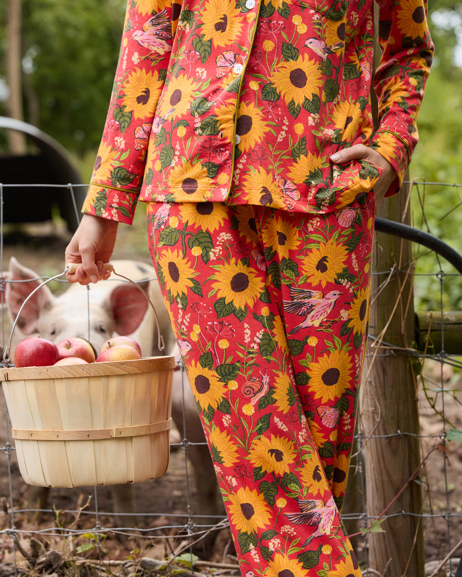 Close view of the orange sunflower-print long pajama set, showing the button-front top, pocket, and matching pants.