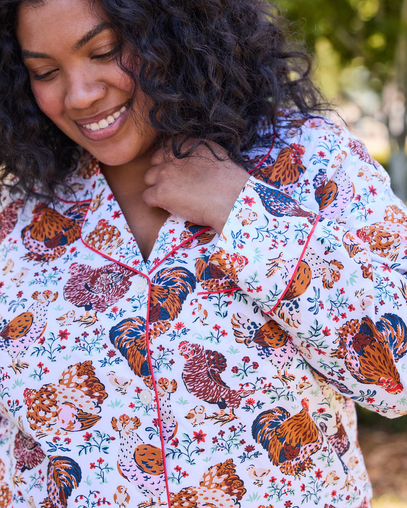 Close-up of the Must Love Chickens pajama top, showing the chicken-and-floral print, notched collar, buttons, and contrasting red piping.