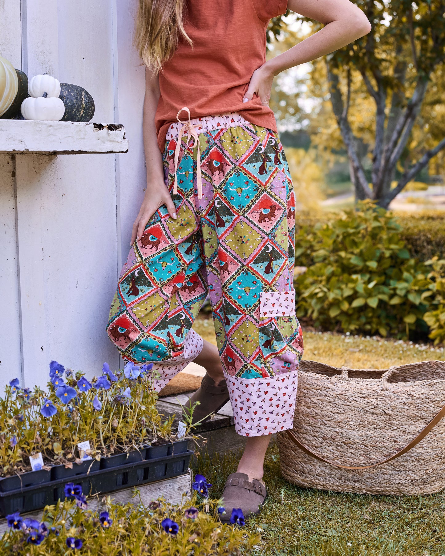 Person wearing cropped printed pants with a drawstring waist, large side pockets, and contrasting patterned cuffs outdoors.