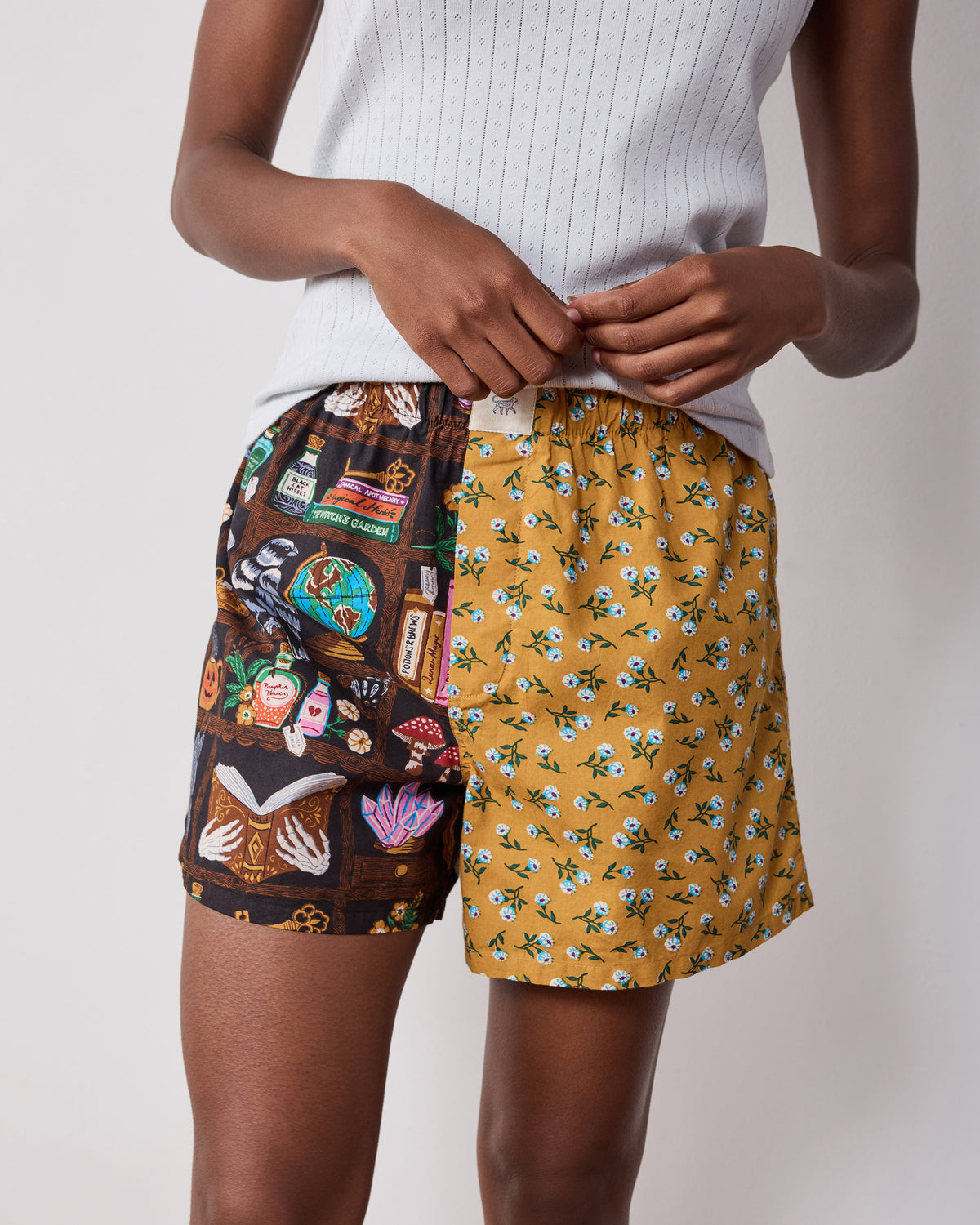 Front view of two-tone boxer shorts with a dark illustrated study print on one side and a floral print on the other.