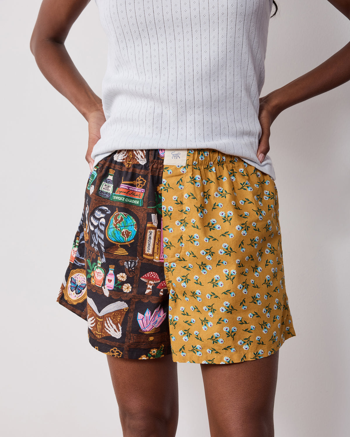 Front close-up of two-tone boxer shorts with a dark illustrated study print and mustard floral print.