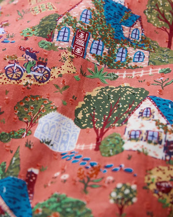 Coral pattern showing illustrated cottages, trees, a greenhouse, a bicycle, and a person walking a dog.
