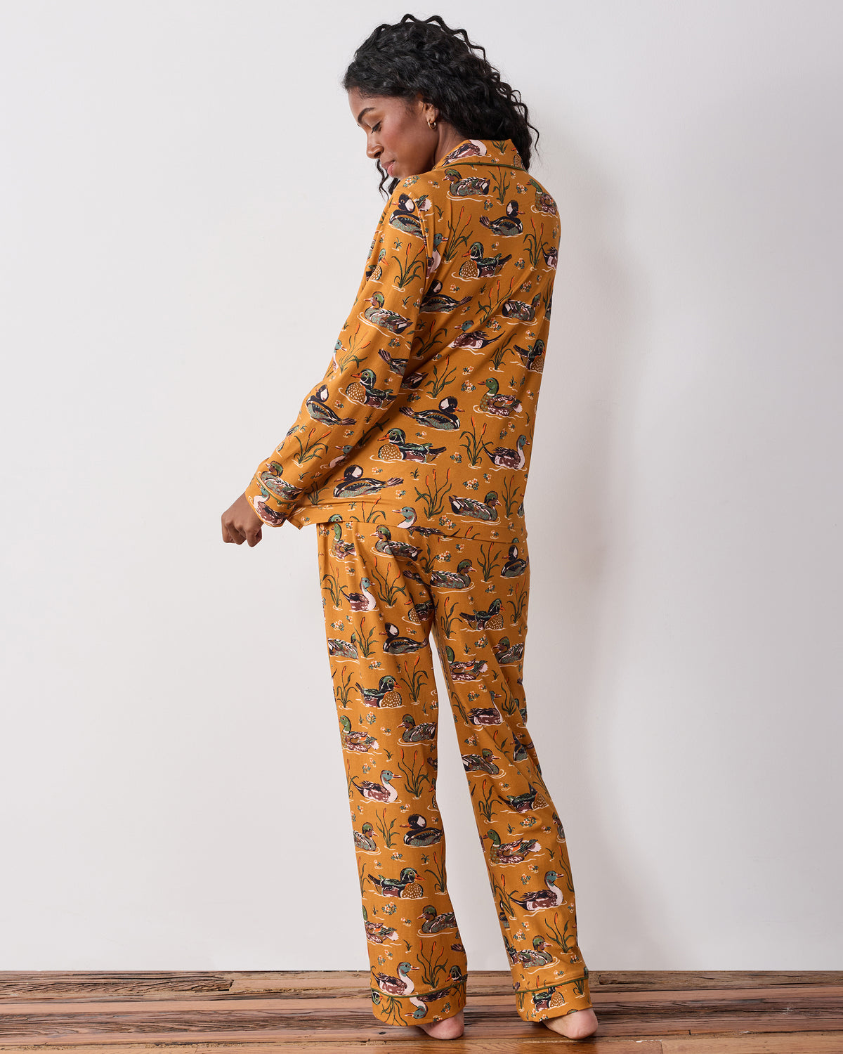 Back three-quarter view of the mustard Duck Pond long pajama set with a duck print, long-sleeve top, and full-length pants.