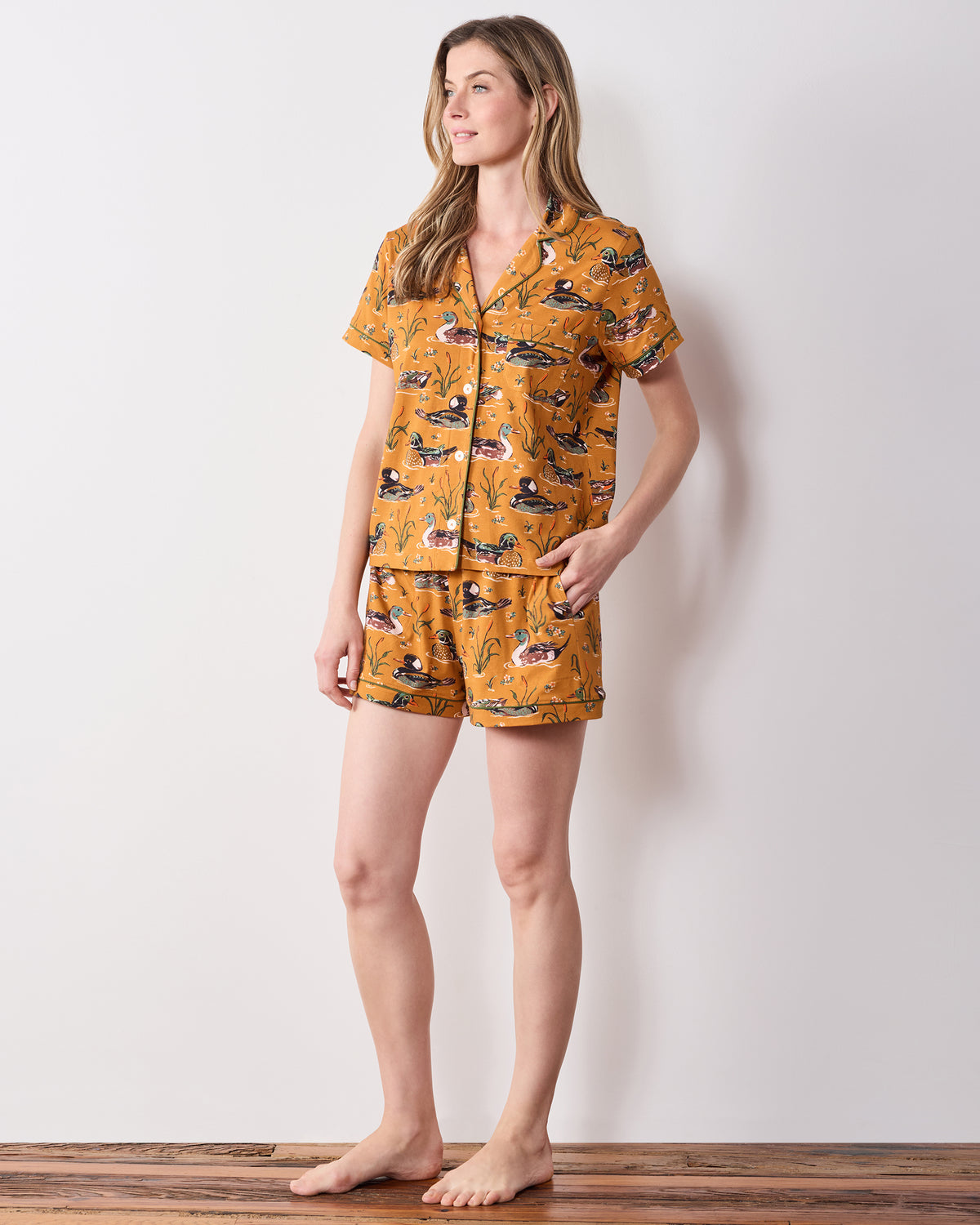 Front three-quarter view of the mustard Duck Pond short pajama set with a duck print, button-down top, and matching shorts.