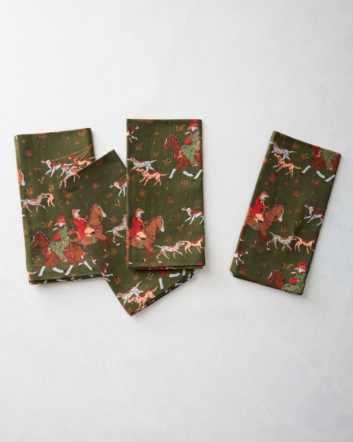 Four folded Fox & Hounds dinner napkins arranged together, showing the horse-and-hounds print.