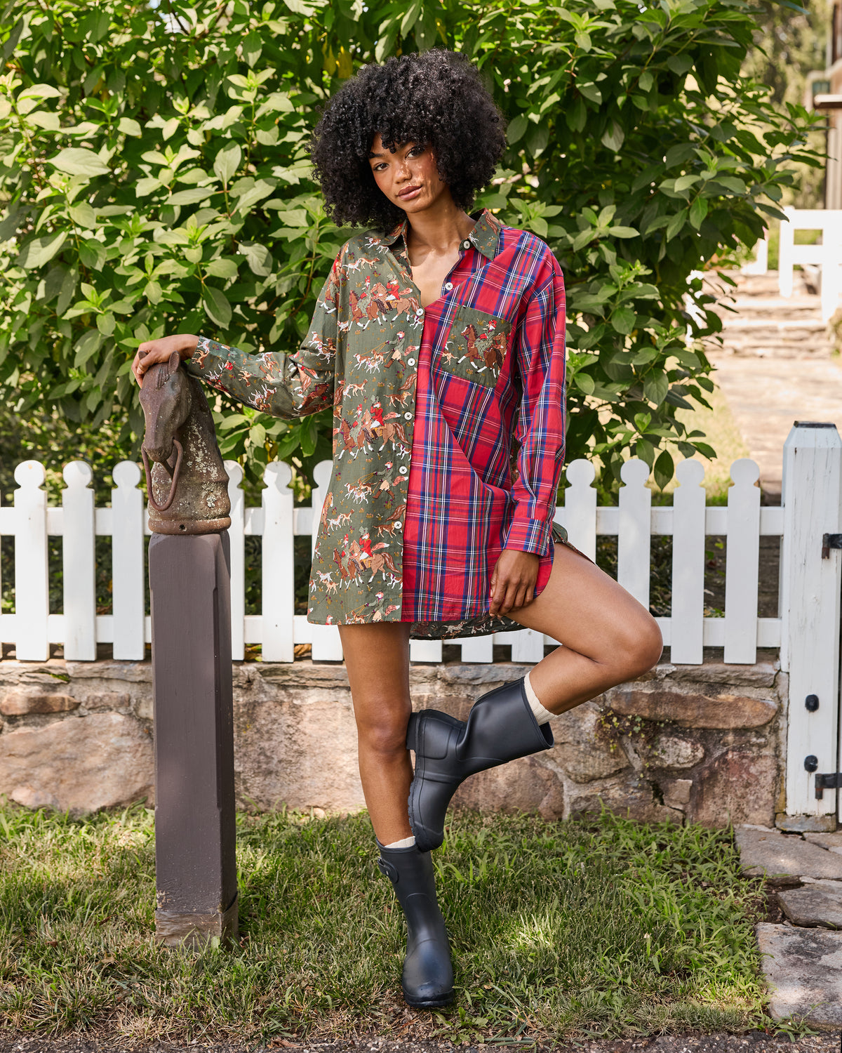 Front view of a long-sleeved button-down shirt combining a green fox-and-hounds print with red plaid, worn outdoors with black boots.