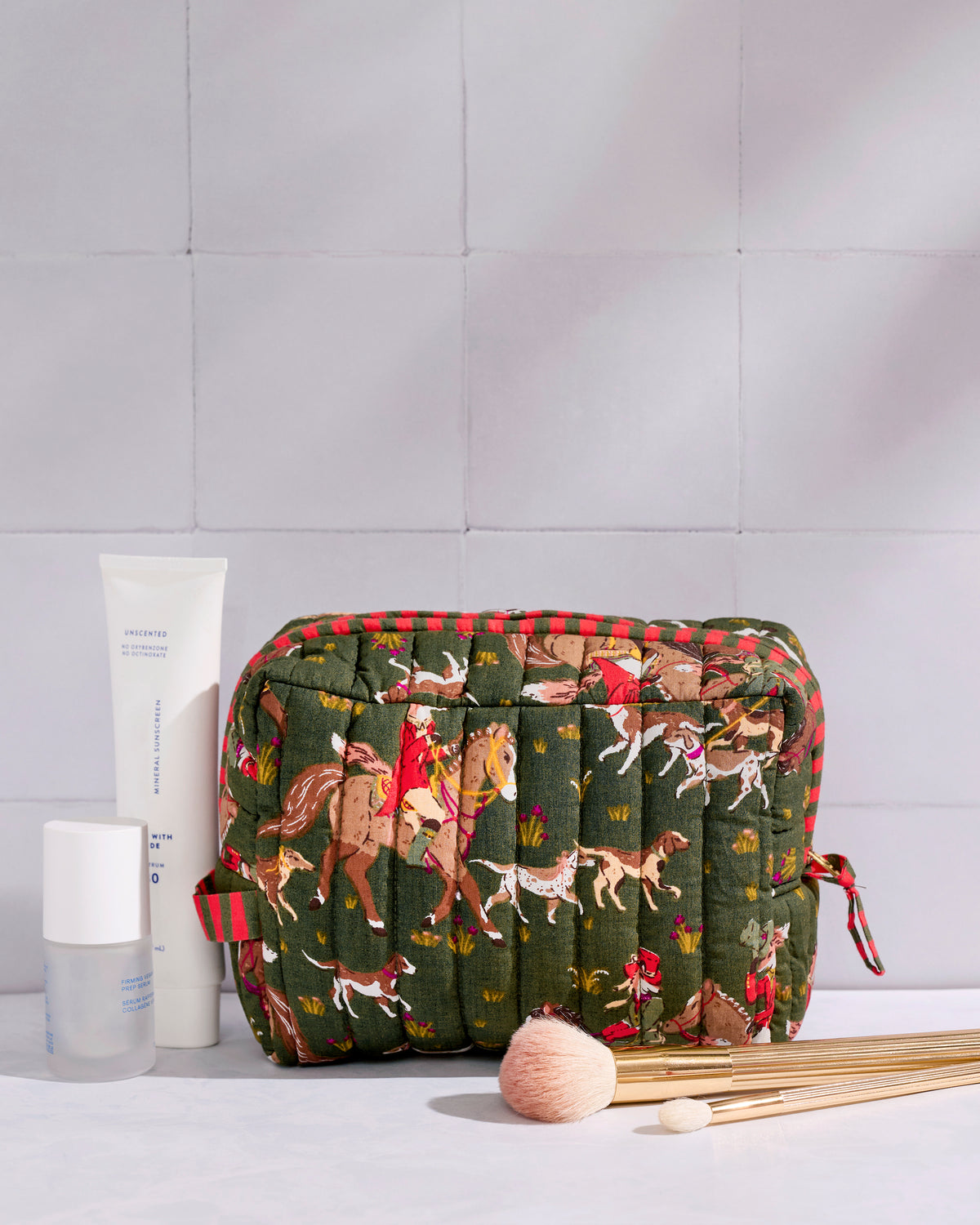 Quilted Pine Grove Fox & Hounds pouch displayed with skincare bottles and makeup brushes.