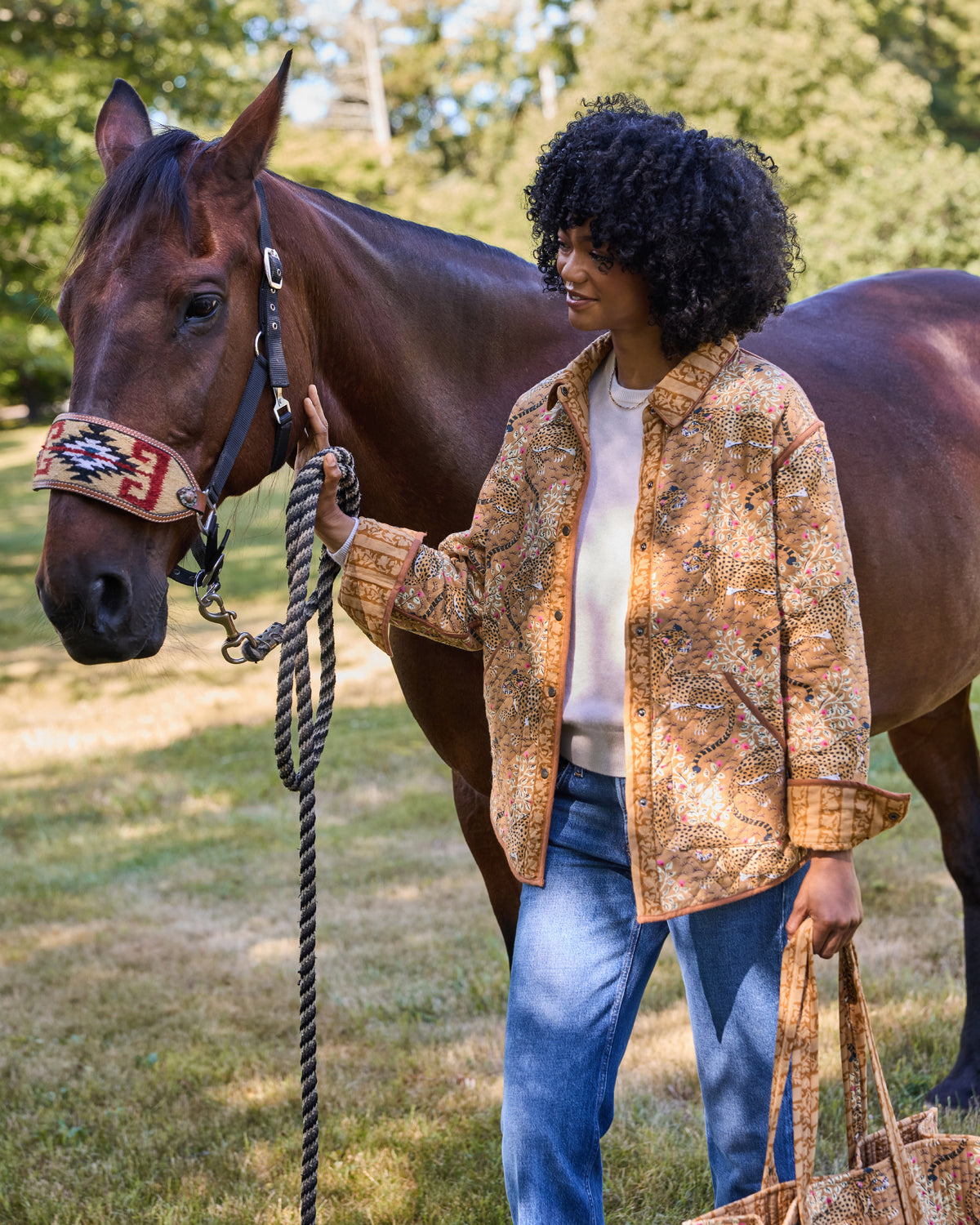 Model wearing the Garden Stripe reversible quilted jacket with jeans and holding a horse's lead rope.