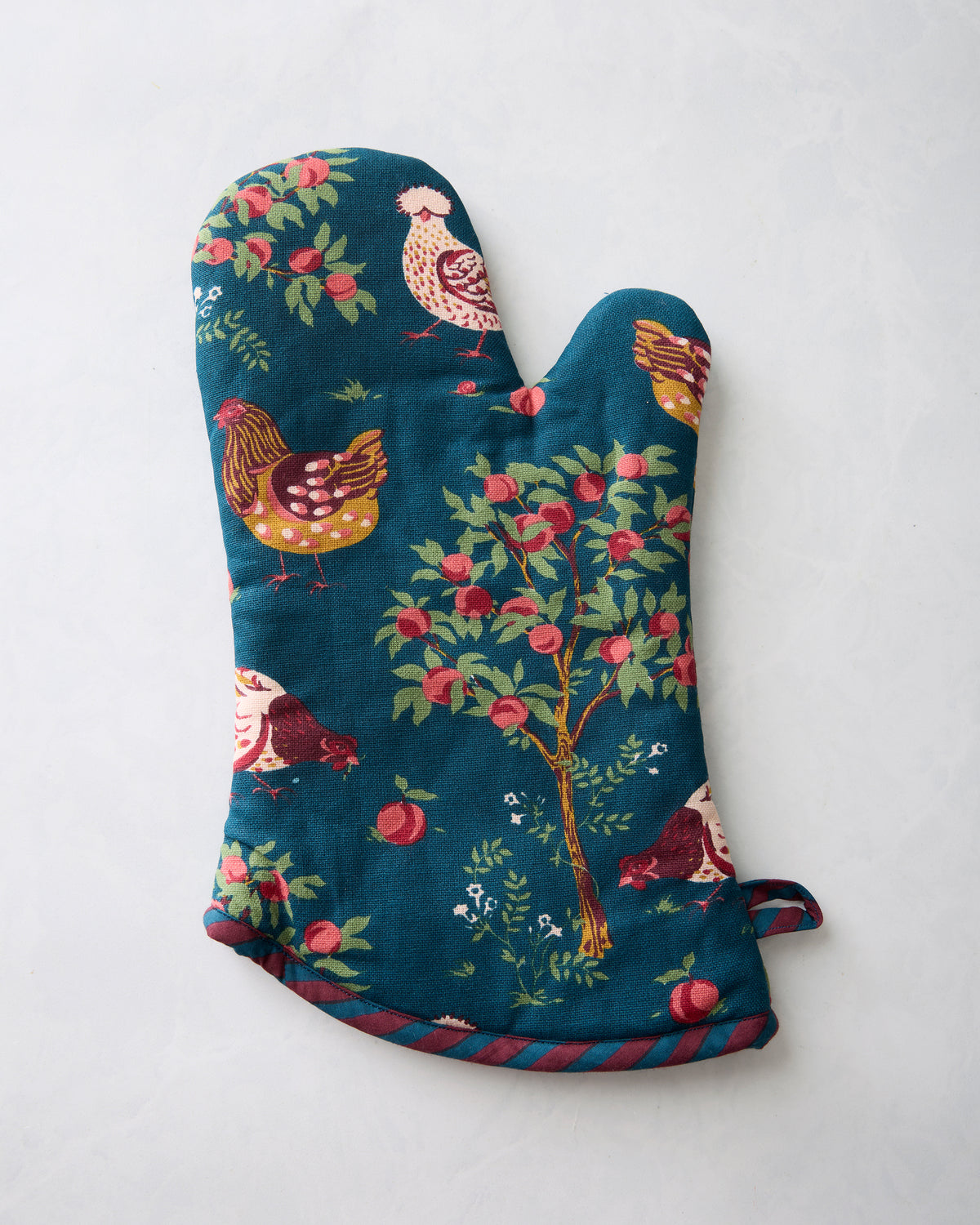 Oven mitt with a dark teal chicken-and-apple-tree print, striped trim, and hanging loop.