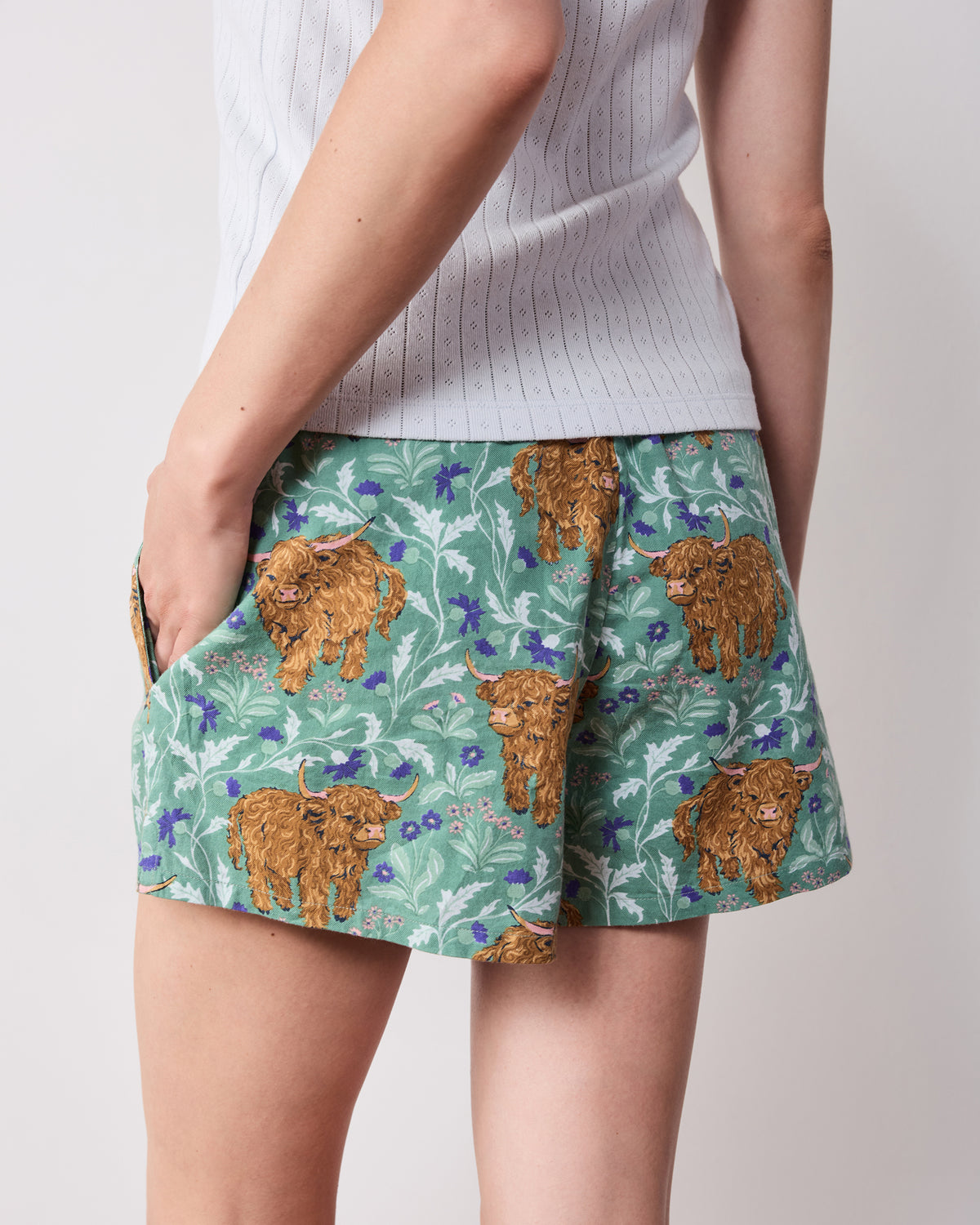 Back view of green Highland cow-print pajama shorts with side pockets
