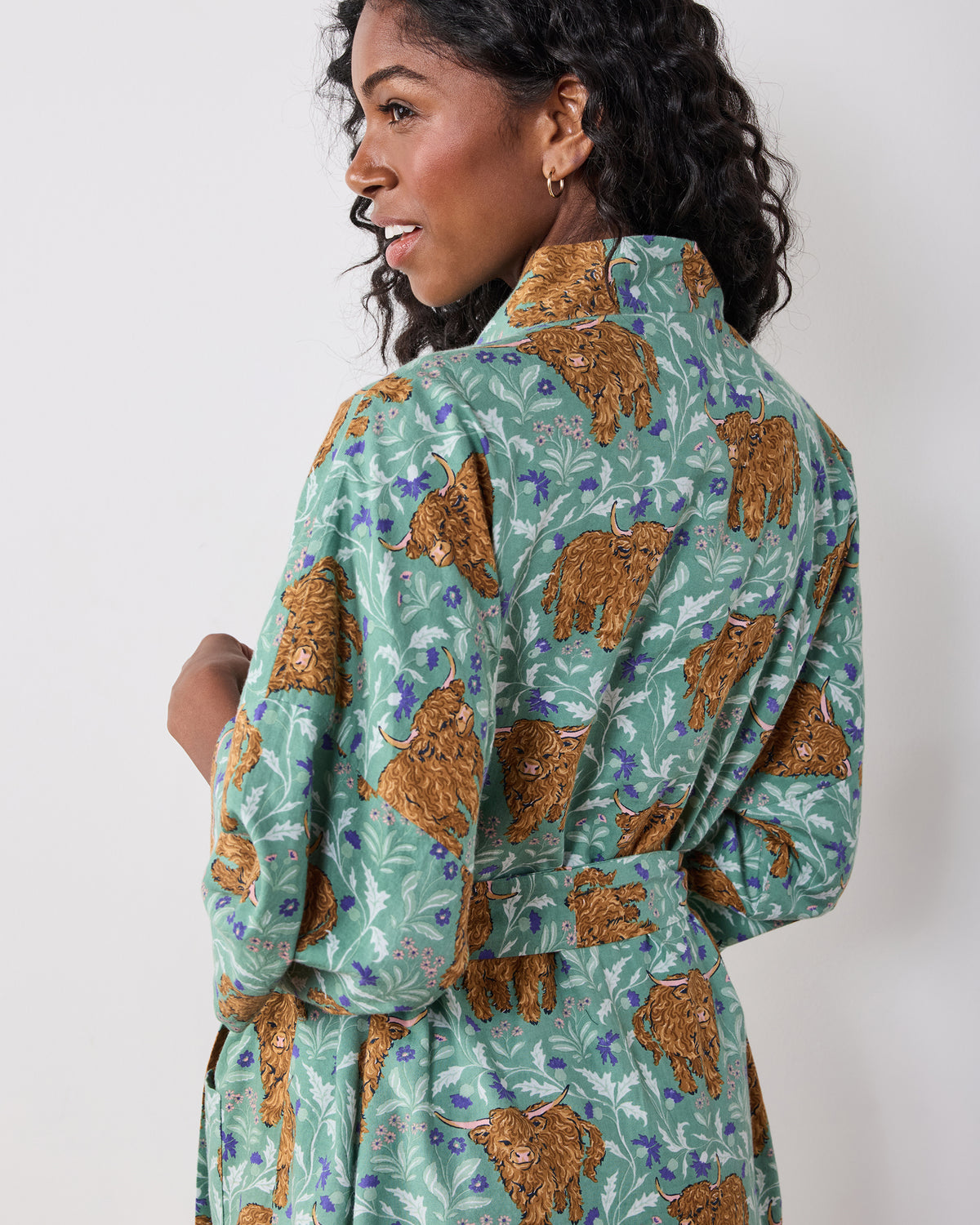 Back view of a green long robe with a Highland cow and leafy floral print, matching belt, and long sleeves.