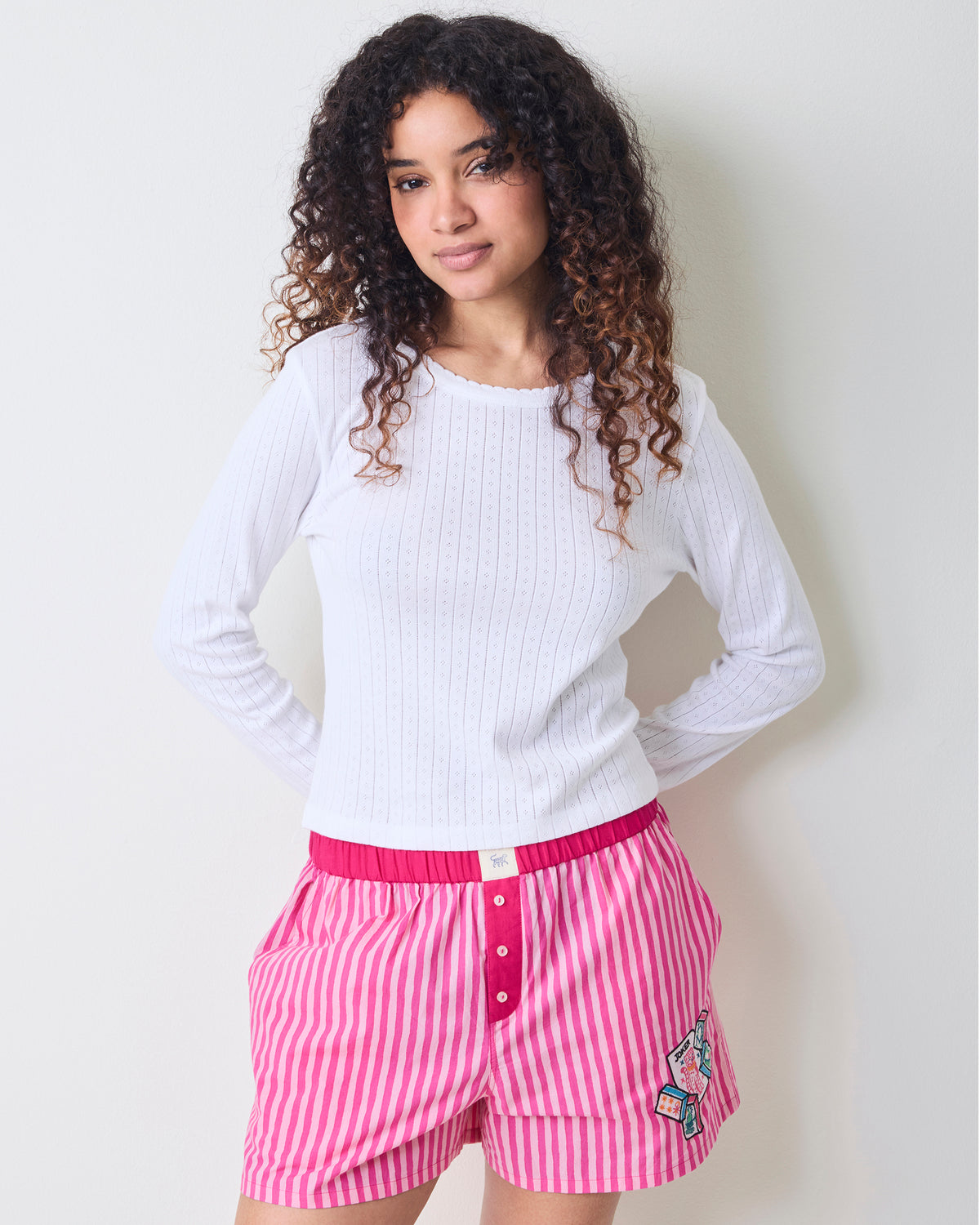 Close front view of the hot pink striped Eloise boxers showing the elastic waistband, button fly, pockets, and embroidered motif.