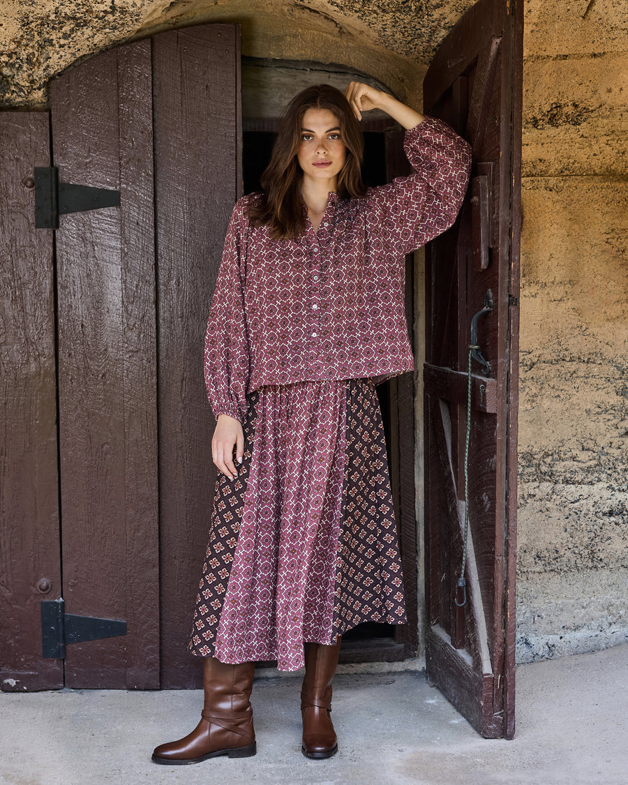 Front view of the patterned Coraline skirt styled with a matching long-sleeve blouse and tall boots.