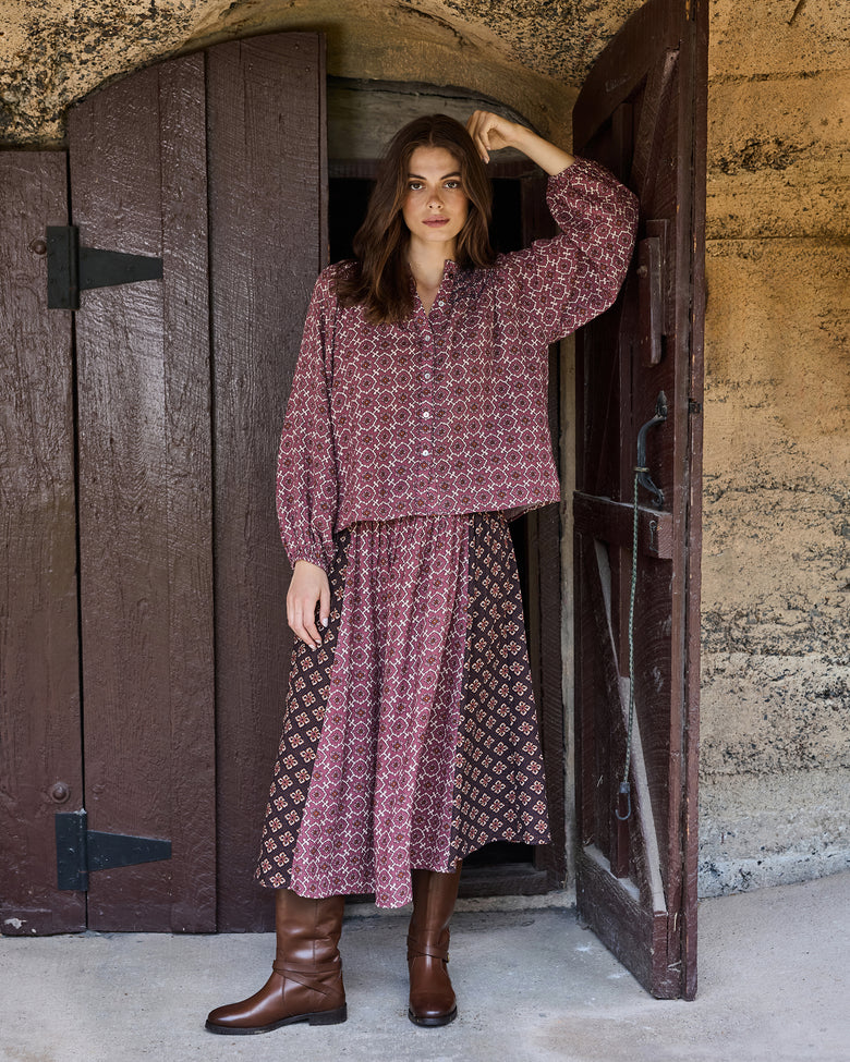 Full-length view of the patterned Aspen blouse styled with a long patterned skirt and brown boots.