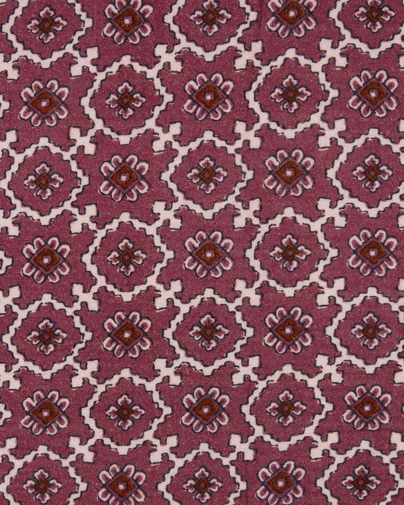 Close-up of mauve fabric with repeating geometric floral motifs in white, pink, and brown.
