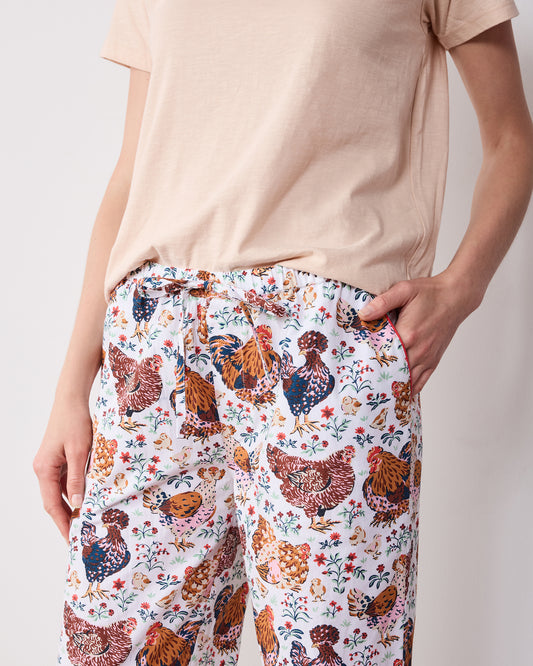 Close-up of printed pajama pants with a drawstring waist, side pockets, and colorful chicken-and-floral pattern.