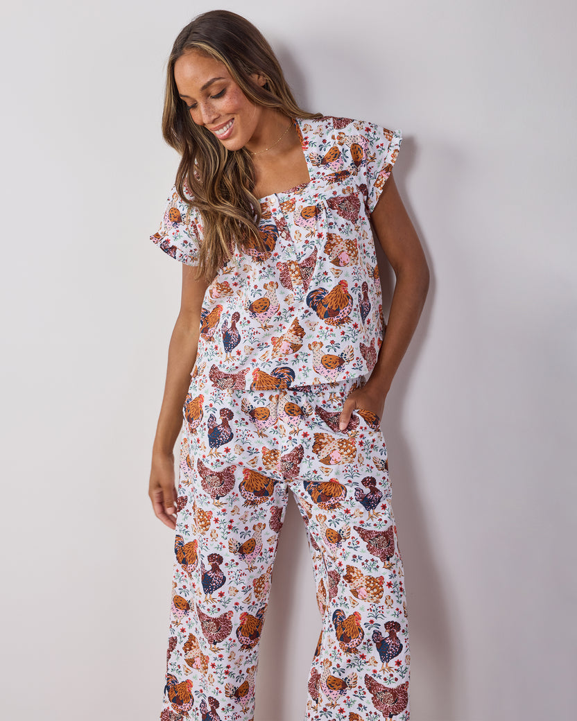 Person wearing a cropped short-sleeve top and matching pants with a colorful chicken-and-floral print.