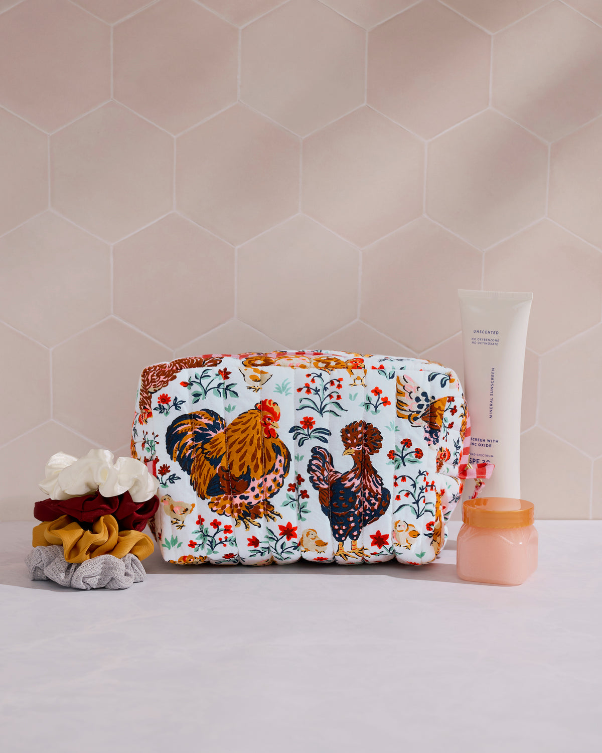Cloud quilted pouch with hens, chicks, and floral motifs, shown with hair scrunchies and toiletry containers.