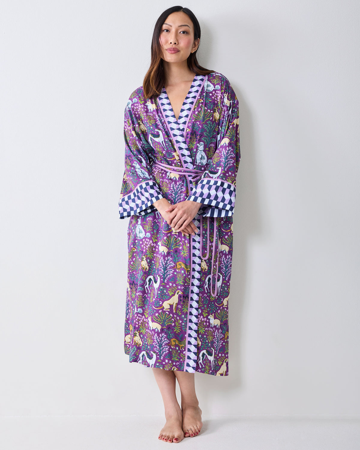 Front view of a person wearing a purple dog-and-floral print wrap robe with contrasting geometric trim, wide cuffs, and a matching belt.