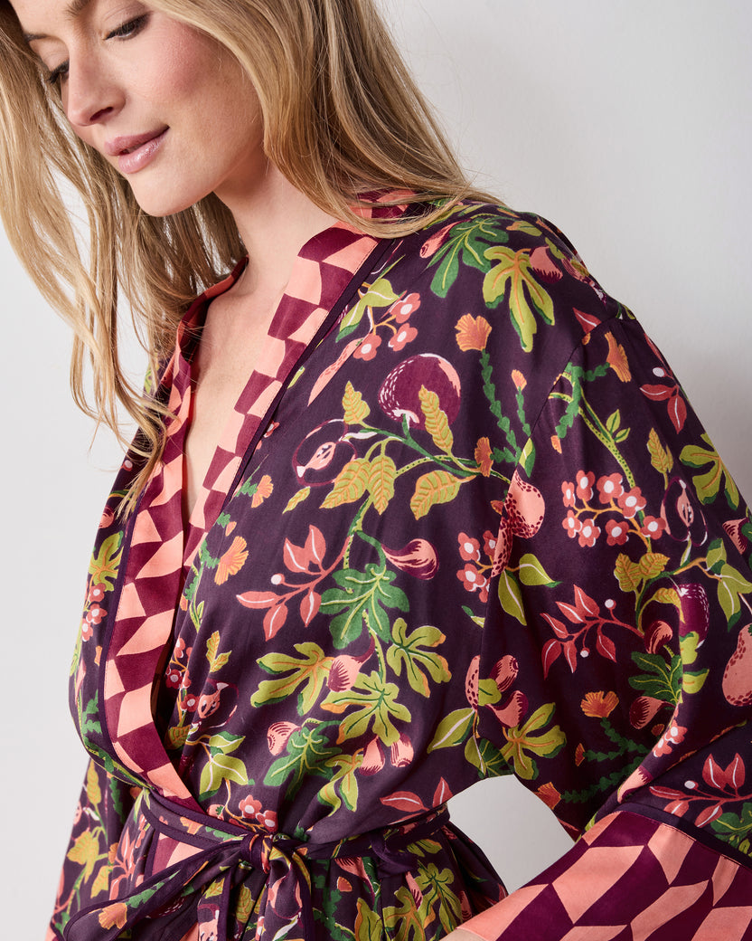 Close view of the plum Pomme & Poire robe showing its open neckline, fruit-and-greenery print, tied belt, and wide contrasting cuff.