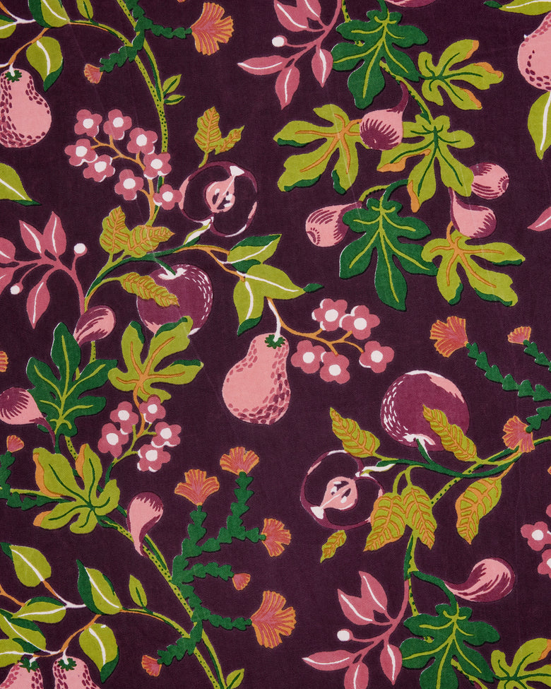 Close-up of a plum-colored print with pink pears, berries, leaves, and flowers.