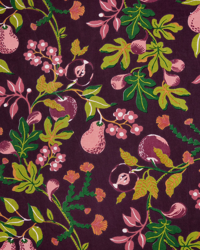 Close-up of a plum-colored print with pink pears, berries, leaves, and flowers.