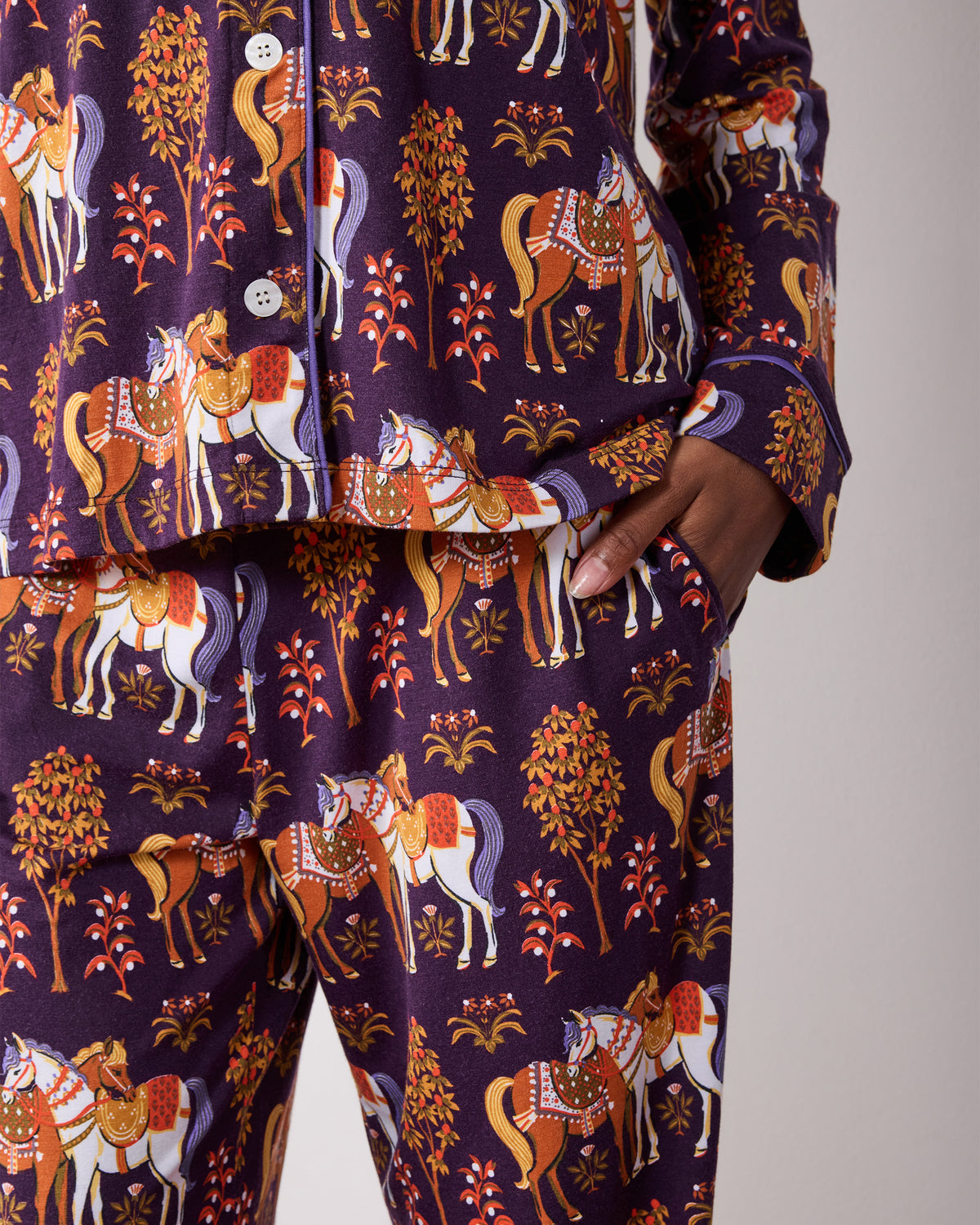 Close view of the long pajama set showing the buttoned top, sleeve cuff, pocket, and matching pants in a horse print.