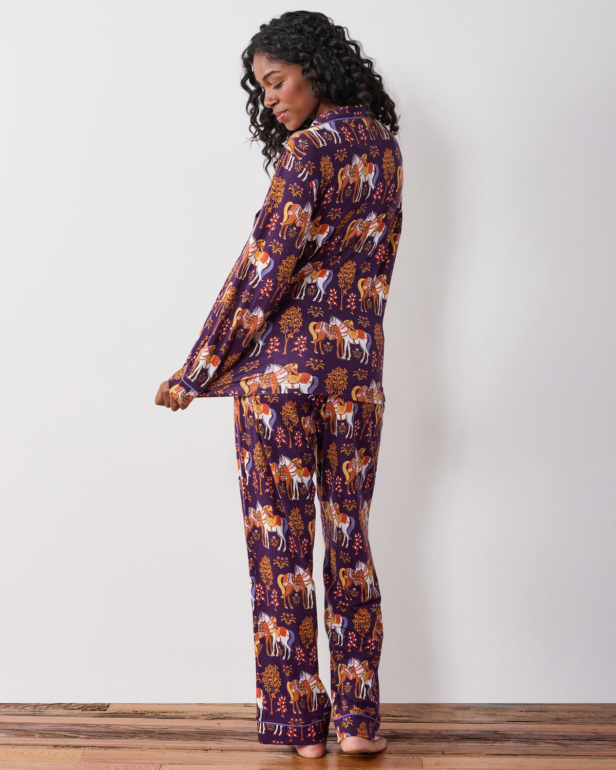 Back view of the long-sleeve pajama set with the horse-and-tree print visible across the top and pants.