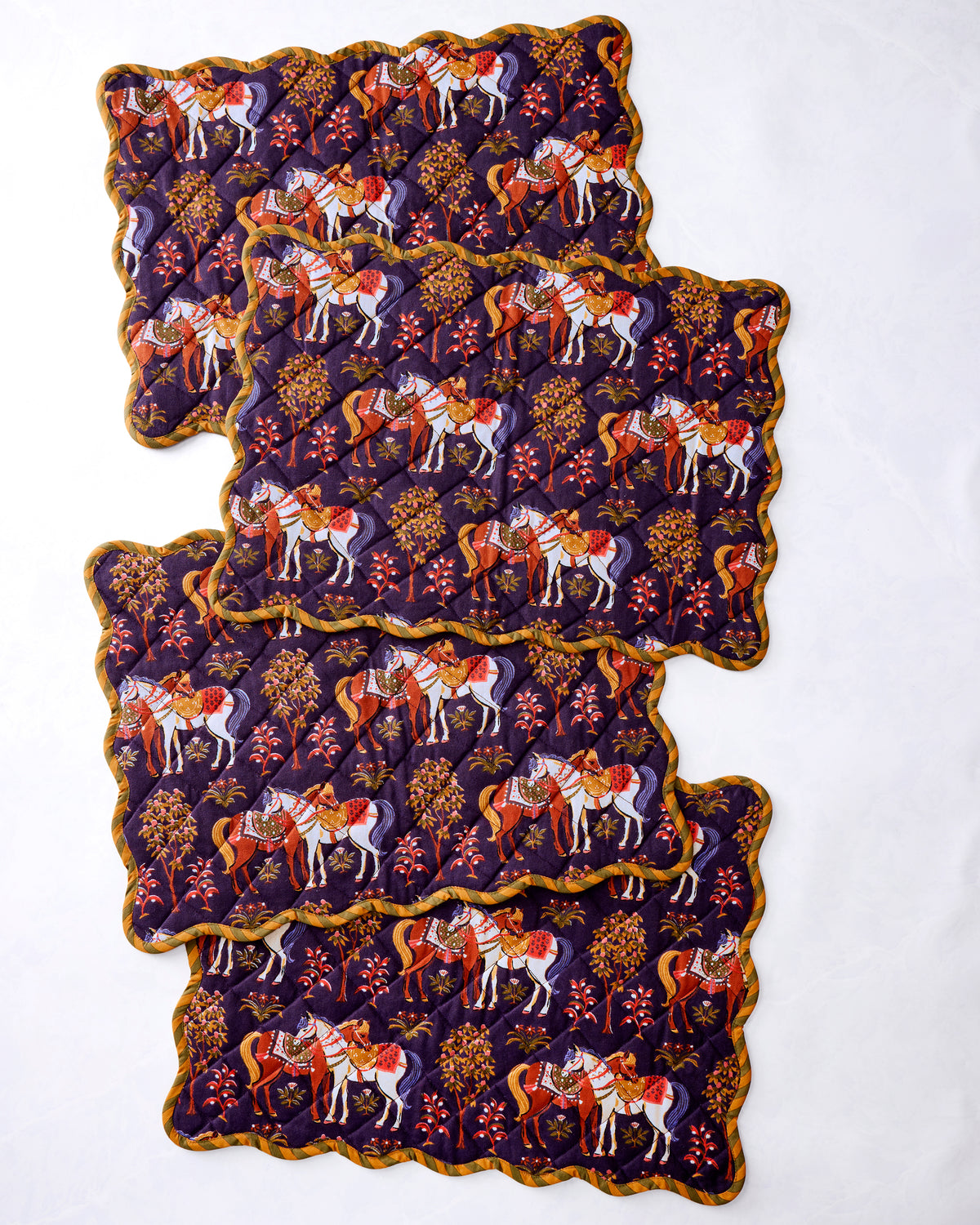 Four scalloped quilted placemats with a horse-and-tree print, layered on a white background.