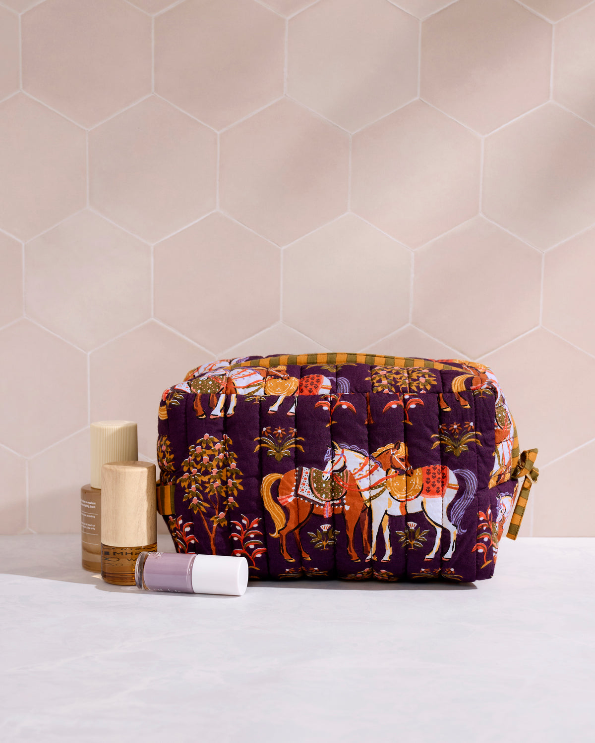 Quilted horse-print pouch beside several toiletry containers on a bathroom counter.