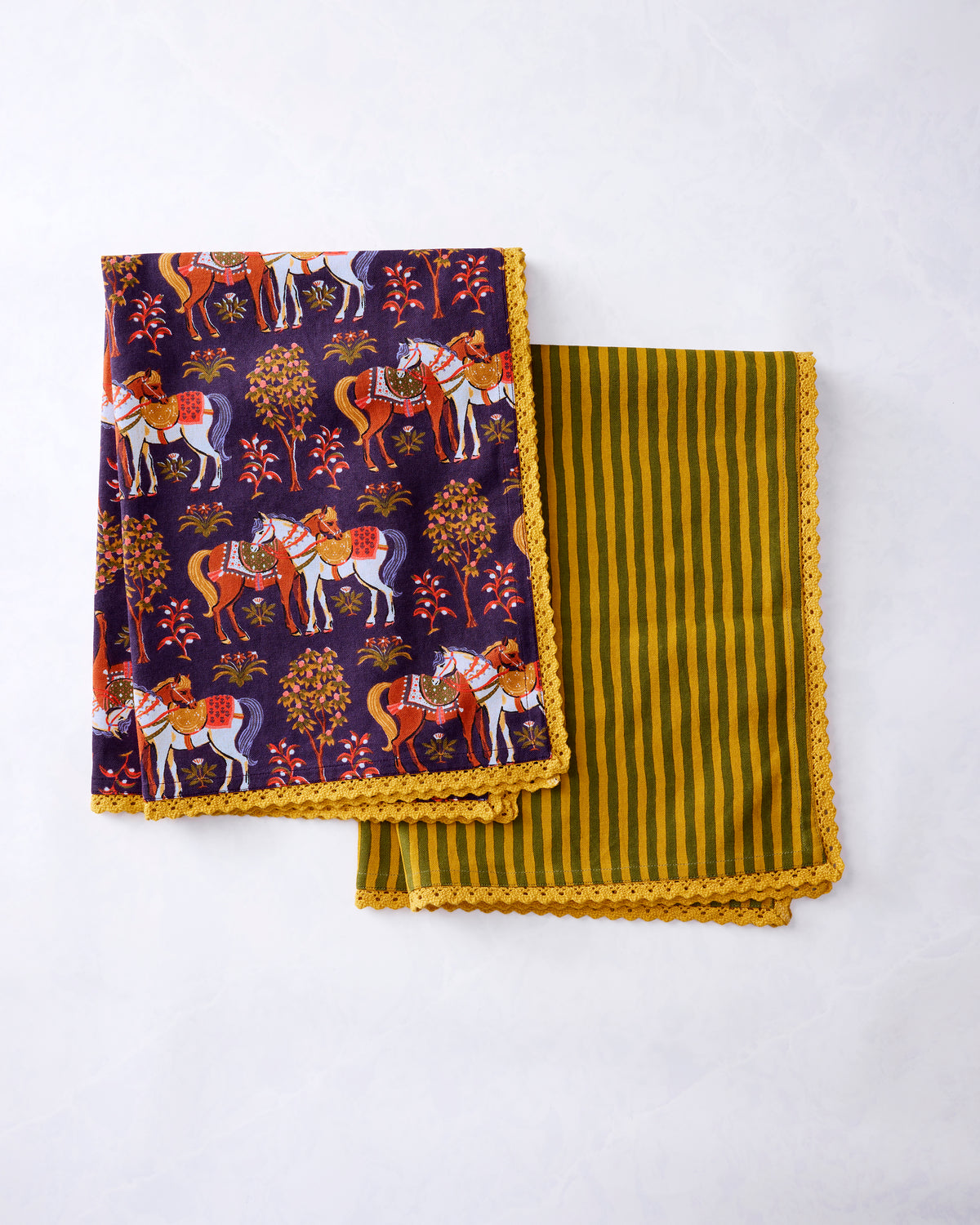 Two kitchen towels with scalloped trim, one featuring a horse-and-floral print and the other green and gold stripes.