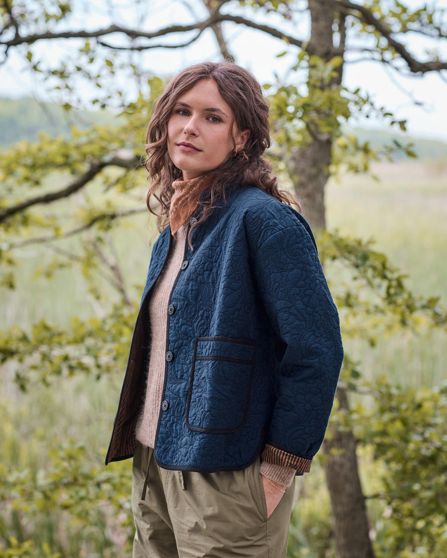 Front three-quarter view of the vintage indigo Elliott jacket with snap buttons, quilted equestrian pattern, and two front patch pockets.