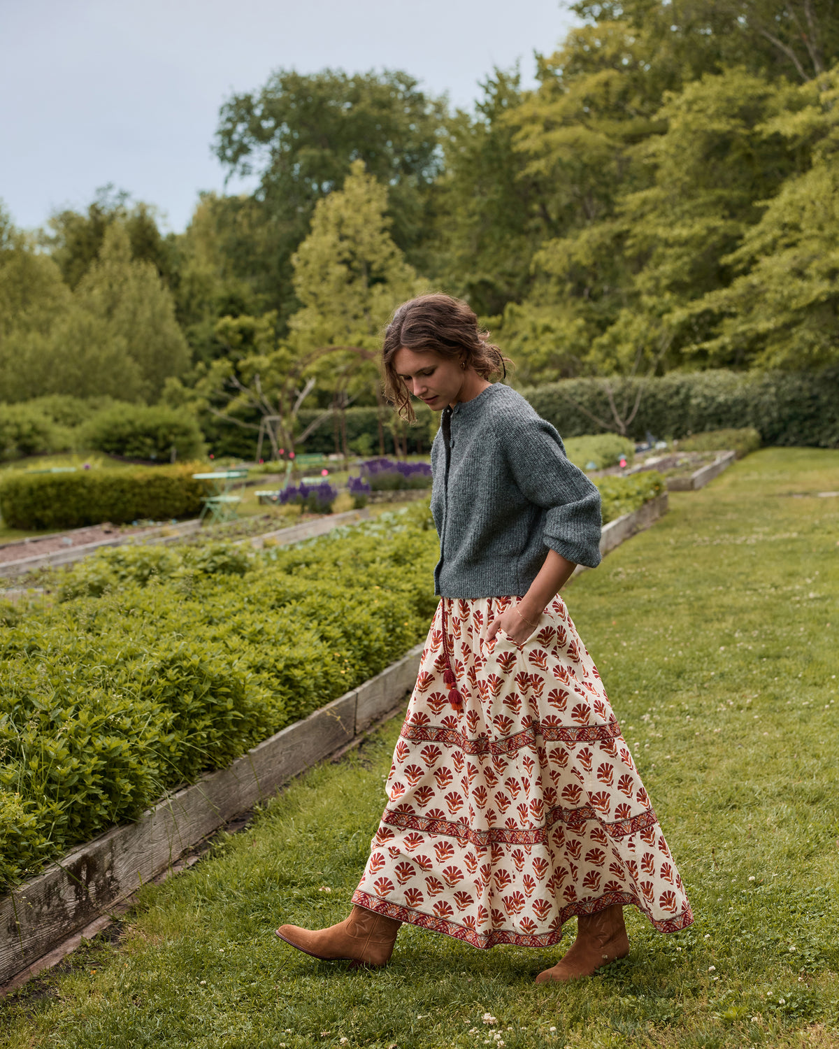Model wearing the Sierra Bloom cream floral-print maxi skirt while walking through a garden.